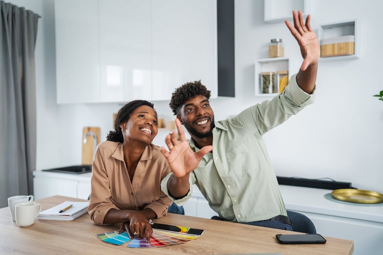 Happy black couple discussing home improvement, choosing paint colors with swatches for their new kitchen design, imagining the future of their renovated space together
